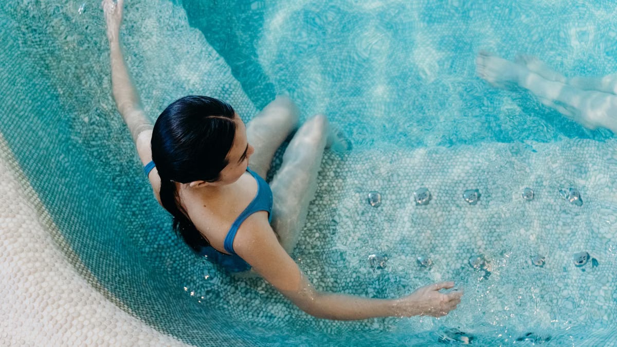 Aerial view of a woman in a blue swimsuit lounging in a swimming pool, capturing a serene moment.